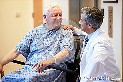 Senior Male Patient Being Pushed In Wheelchair By Doctor Stock Photo