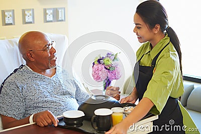 Senior Male Patient Being Served Meal In Hospital Bed Stock Photo