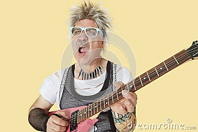 Senior male punk musician playing guitar over yellow background Stock Photo
