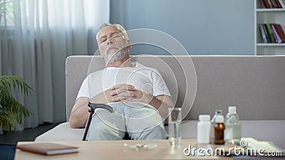 Senior male sleeping on sofa at home, relax after taking pills, medication Stock Photo