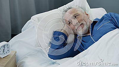 Senior male waking up and smiling after comfortable healthy sleep, health care Stock Photo