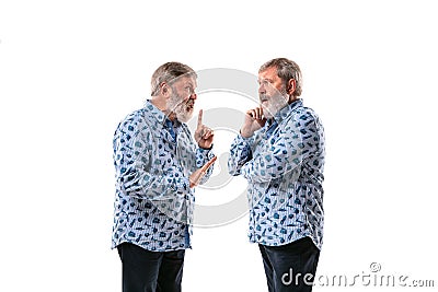 Senior man arguing with himself on white studio background. Stock Photo
