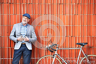 Senior man with bicycle standing against brick wall. Stock Photo