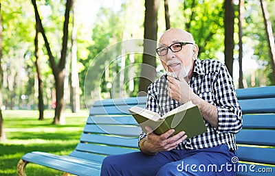 Elderly man in casual reading outdoors Stock Photo