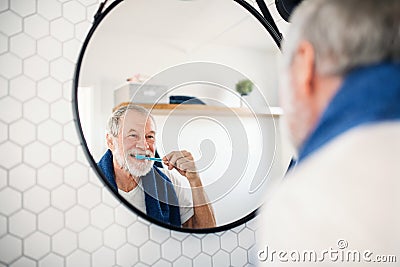 A senior man brushing teeth in bathroom indoors at home. Copy space. Stock Photo