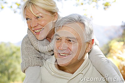 Senior man carrying his wife around on his back Stock Photo