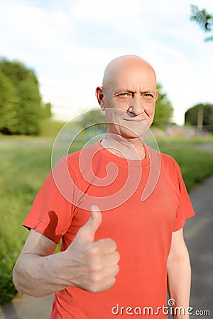 Senior man in casual wear stands smiling and showing thumb up to camera Stock Photo