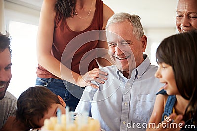 Senior man celebrating his birthday with family after blowing out candles on birthday cake, close up Stock Photo