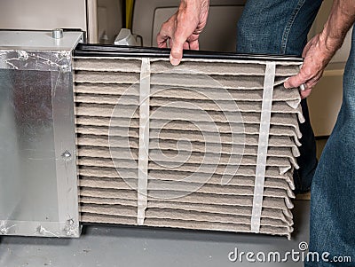 Senior man changing a dirty air filter in a HVAC Furnace Stock Photo