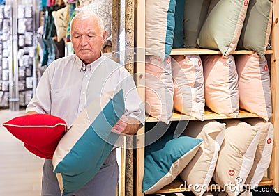 Senior man choosing pillow at household shop Stock Photo