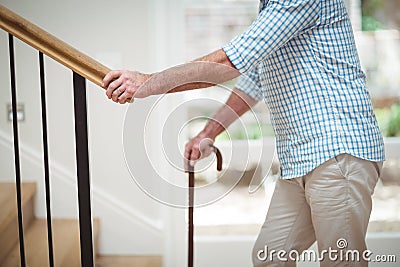 Senior man climbing upstairs with walking stick Stock Photo