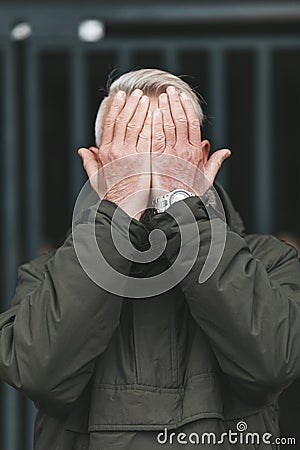 The senior man covered his face with his hands. Age crisis, depression in people. Adult mistakes and despair Stock Photo