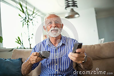 Senior man enjoys watching tv at home. Stock Photo