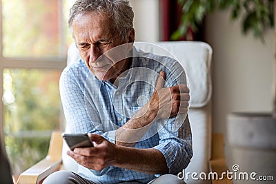 Senior man experiencing pain while using a smartphone Stock Photo