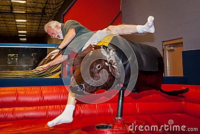 Senior Man Falls Off Mechanical Bull Stock Photo