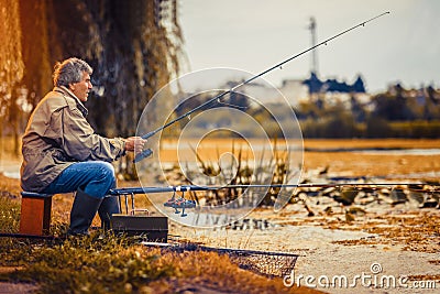 Senior man fishing on a freshwater lake sitting patiently Stock Photo