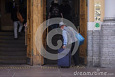 A senior man in funny hat, wearing mask is going to travel Editorial Stock Photo