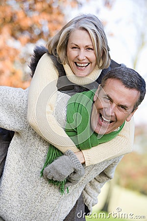 Senior man giving woman piggyback ride Stock Photo