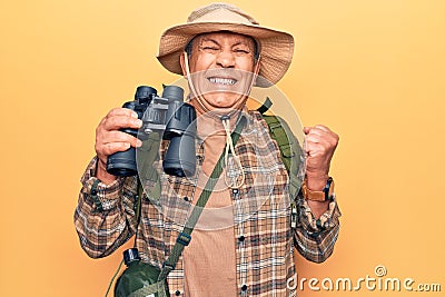 Senior man with grey hair wearing hiker bakcpack holding binoculars screaming proud, celebrating victory and success very excited Stock Photo
