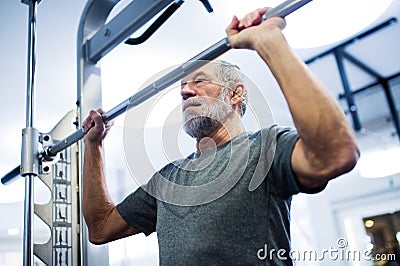 Senior man in gym doing pull-ups on horizontal bar. Stock Photo