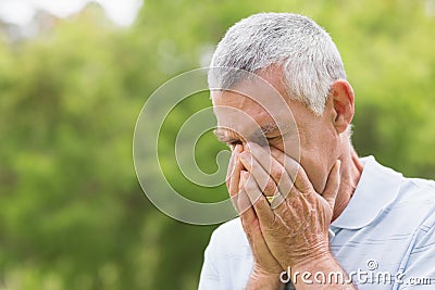 Senior man with head in hands at park Stock Photo