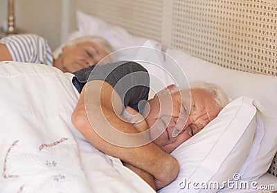 Senior man and his wife asleep in bed at home Stock Photo