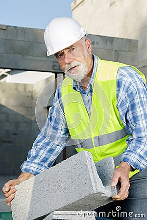 senior man holding bloc cement outdoors Stock Photo