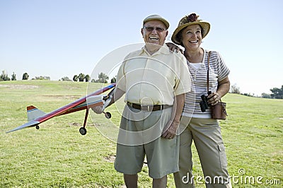 Senior Man Holding Model Plane By Woman On Field Stock Photo
