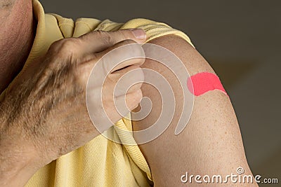 Senior man holding up shirt after flu injection Stock Photo