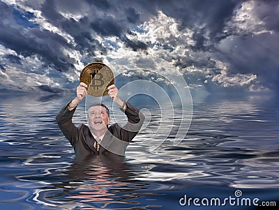 Senior man holds up bitcoin and drowns in ocean Stock Photo