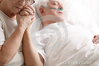 Senior man in hospital bed and his wife holding his hand Stock Photo