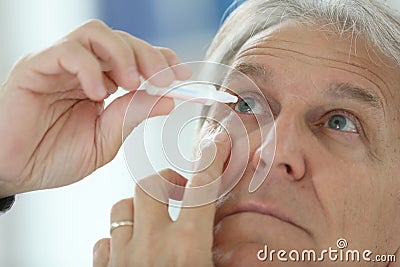 Senior man injecting serum in his eyes Stock Photo