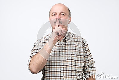 Senior man making silence gesture, keep it in secret Stock Photo