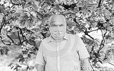 senior man in medical mask. old man walking in park. life during coronavirus lockdown. enjoy sakura beauty. fear of Stock Photo