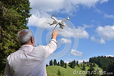 Senior man navigates unmanned aerial vehicle among nature Stock Photo