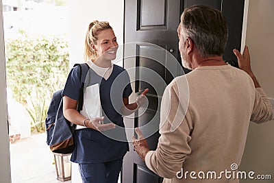 Senior man opening his front door to a female healthcare worker making a home health visit Stock Photo