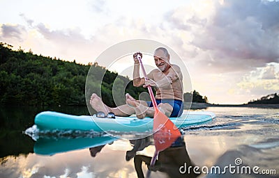 Senior man paddleboarding on lake in summer. Copy space. Stock Photo