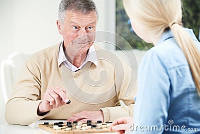 Senior Man Playing Checkers With Teenage Daughter Stock Photo