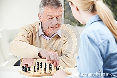 Senior Man Playing Chess With Teenage Granddaughter Stock Photo