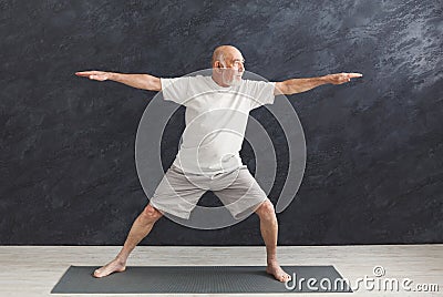 Senior man practicing yoga indoors Stock Photo