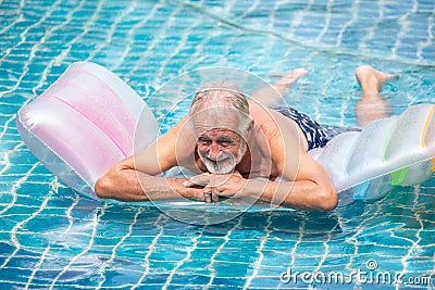 Senior man Relaxing on Inflatable air mattress in swimming pool. take a break , rest , retirement,workout,fitness,sport,exercise Stock Photo