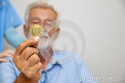 Senior man`s hand holding bitcoin coin. Senior businessman hold a gold bitcoin coin in hand. Cryptocurrency business concept. Elec Editorial Stock Photo