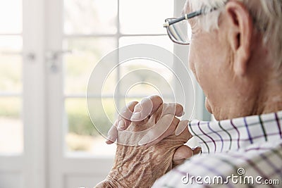 Senior man sits looking out of the window at home, close up Stock Photo