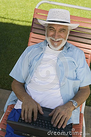 Senior Man sitting on Lawn Chair Using Laptop elevated view portrait. Stock Photo