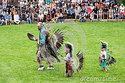 Senior man and small native boys dressed in ceremonial costume for the annual pow wow dancing in an arena Editorial Stock Photo