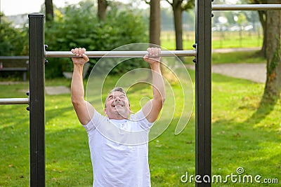 Senior man straining to pull himself up by the arms Stock Photo