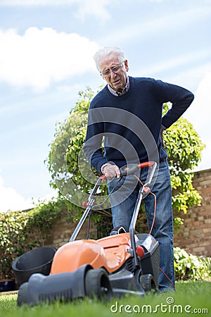 Senior Man Suffering With Backache Whilst Using Electric Lawn Mo Stock Photo