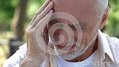 Senior man suffering headache, migraine attack during walk, risk of thrombus Stock Photo