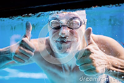 Senior man swimming in an indoor swimming pool. Stock Photo