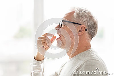 Senior man taking medicine pill at home Stock Photo